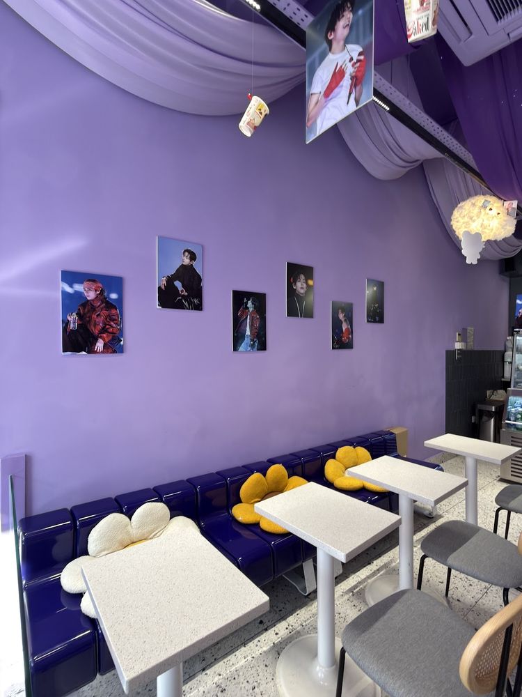 The purple interior with white tables, yellow cushioned bench seating and small photo prints pinned on the wall.